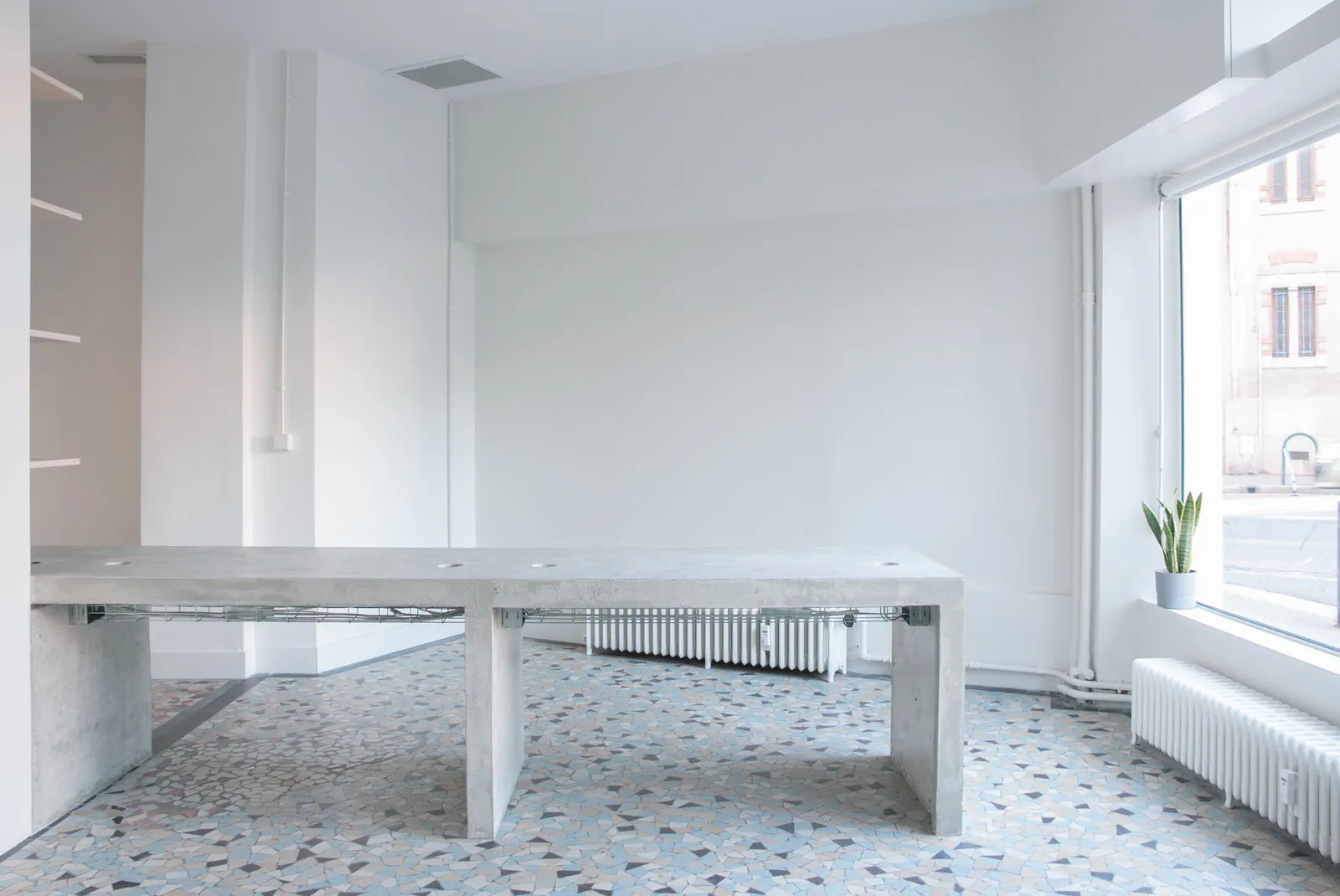 Larousse — Comptoir en béton sur sol en terrazzo, devant la vitrine