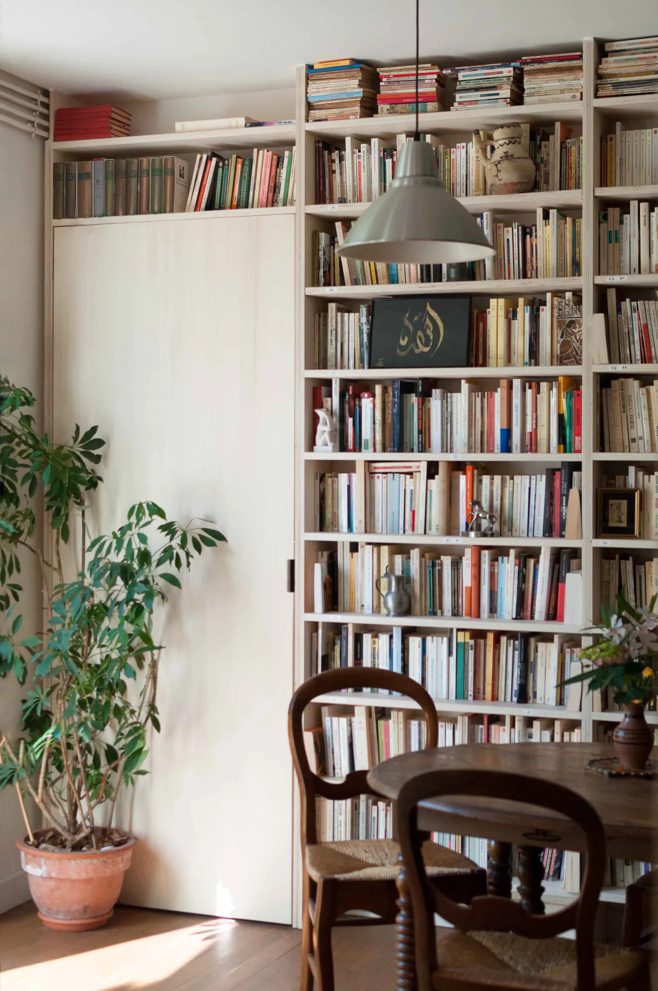 Nîmes — Bibliothèque toute hauteur, table ronde et grande plante
