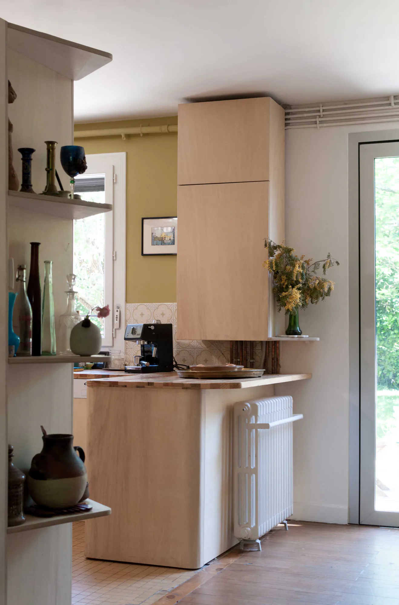 Nîmes — Cuisine en bois clair vue depuis la pièce de vie, porte-fenêtre sur le jardin
