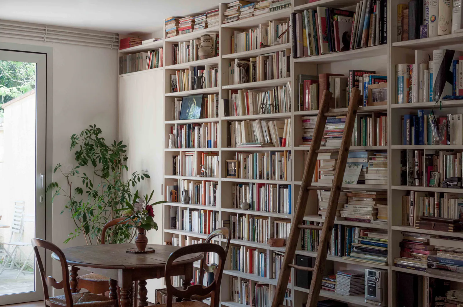 Nîmes — Bibliothèque avec échelle, table ronde et porte-fenêtre sur le jardin
