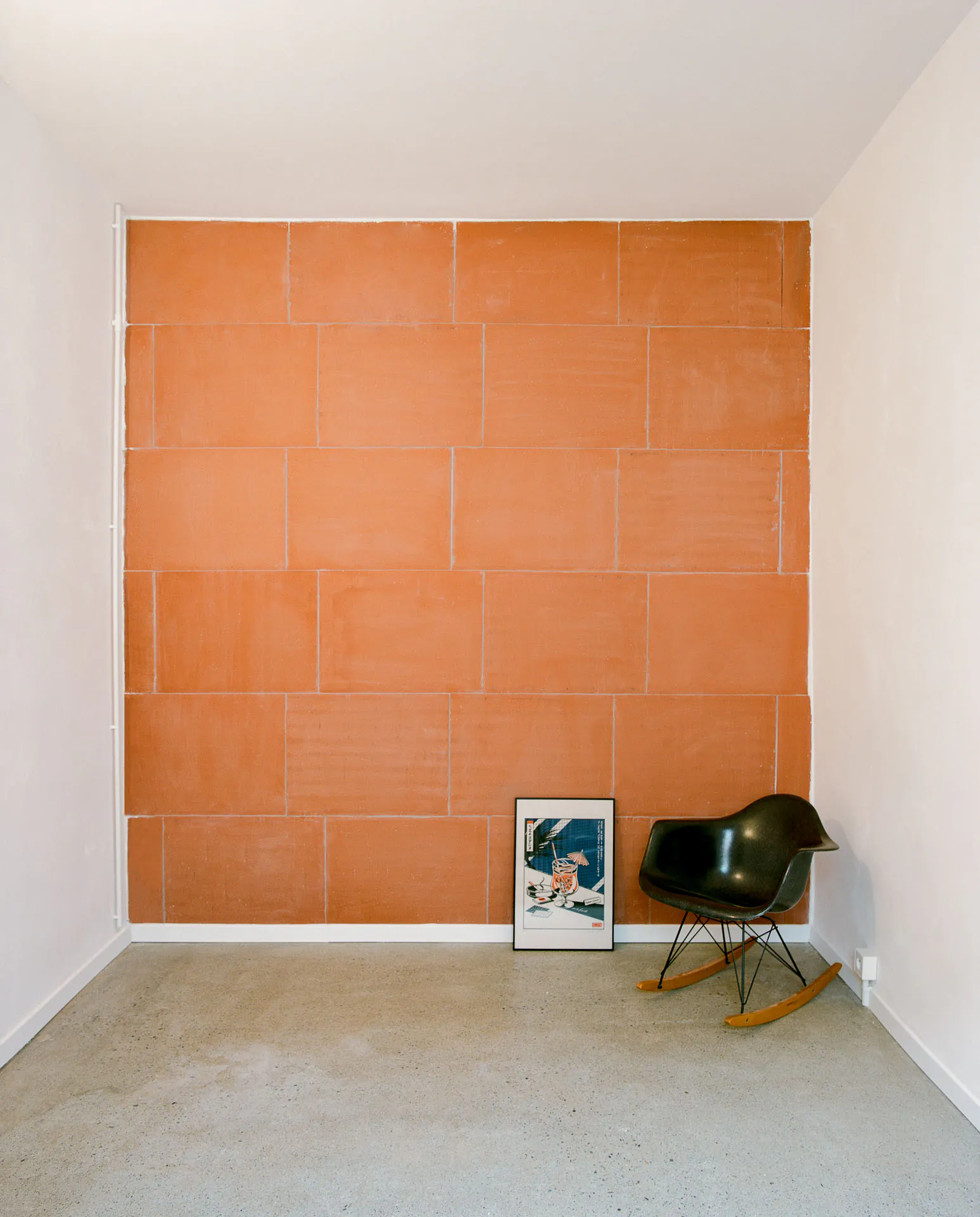 Solférino — Mur de briques orangées laissées apparentes et fauteuil à bascule noir