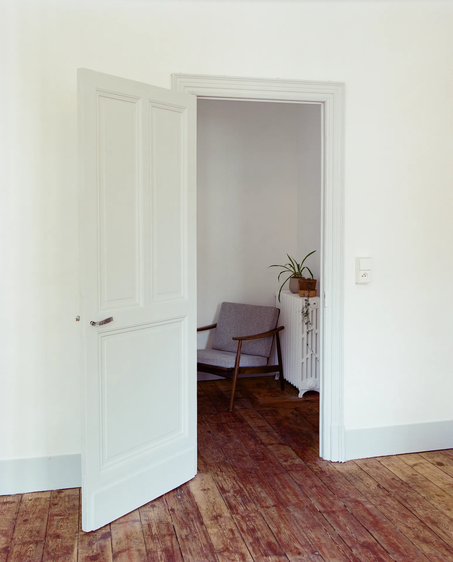 Solférino — Double porte blanche ouverte sur une pièce au parquet ancien